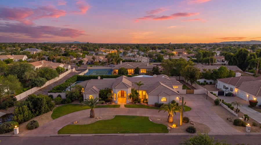 Virtual twilight aerial of an estate with a circular drive and palms