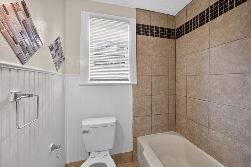 Bathroom with tiled shower, toilet and window at 1473 State St W, Jacksonville, FL 32209