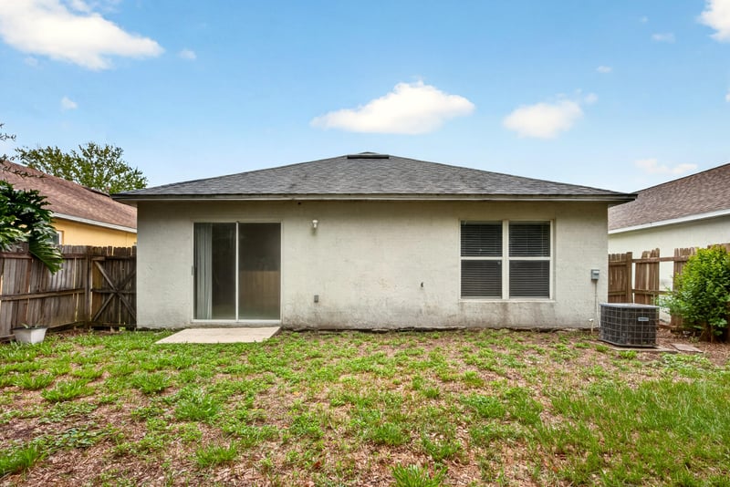 Back exterior with sliding glass door and small yard at 7329 Lawn Tennis Ln, Jacksonville, FL