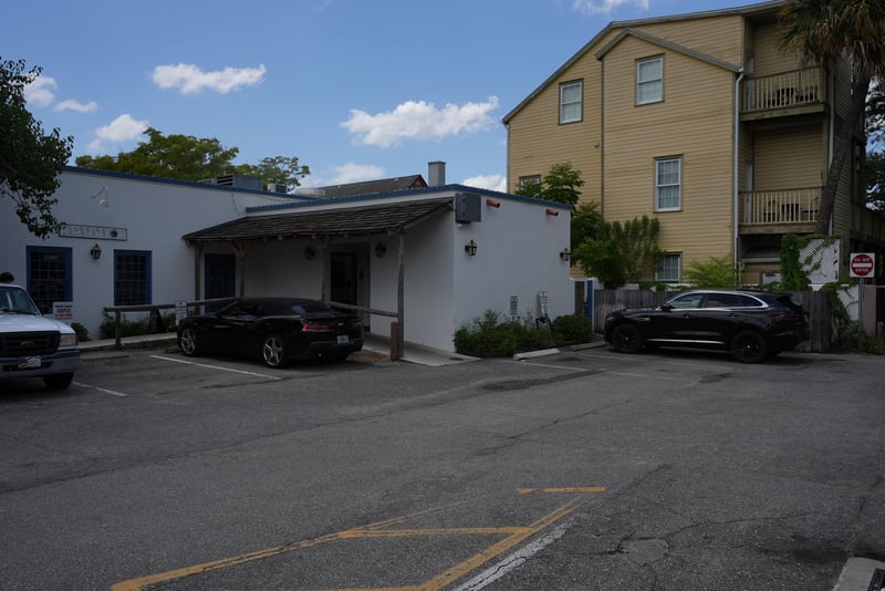 White building corner with parked vehicles and balcony above at 29 Cuna St, St. Augustine, FL 32084