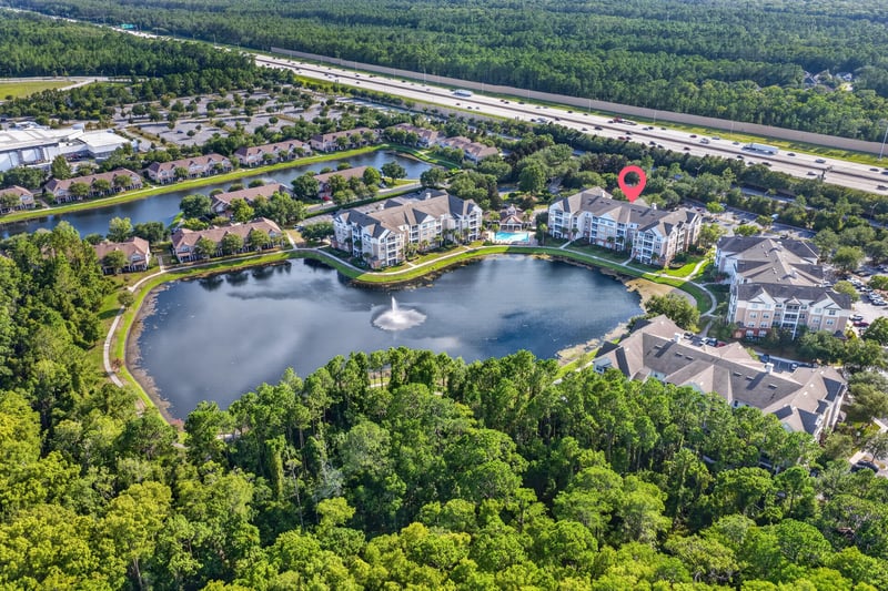 Wide aerial view of the community with lake and nearby road in Jacksonville, FL