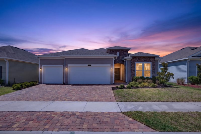 Front exterior at day-to-dusk with illuminated windows at 9942 Lovage Ln, Jacksonville, FL 32219