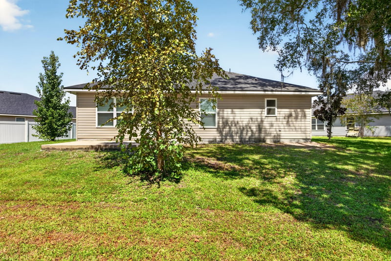 Rear exterior with mature tree and lawn at 9846 Olivia St, Jacksonville, FL