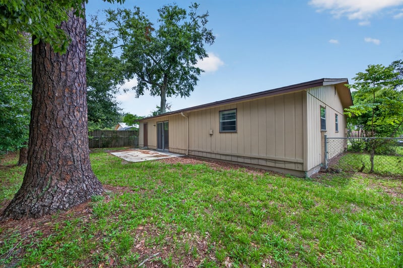 Backyard lawn with trees and side exterior at 1083 Stokes St, Jacksonville, FL