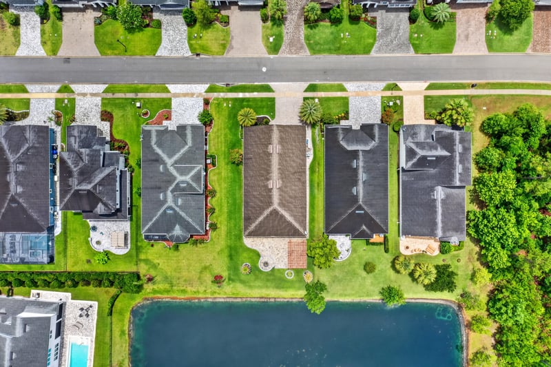 Aerial close view of rooftops and backyard pond in St. Johns, FL