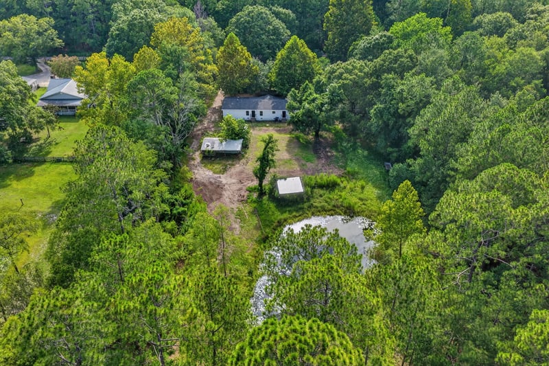 Aerial view of the pond and home among trees at 55520 Jewel-Thomas Rd, Callahan, FL 32011
