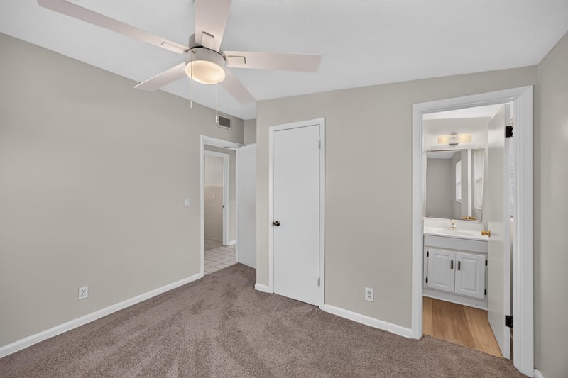 Carpeted bedroom with ceiling fan leading to bathroom at 87 Saratoga Cir S, Atlantic Beach, FL