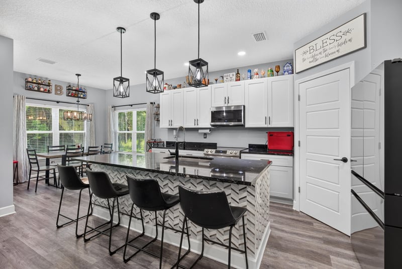 Kitchen island with black bar stools and pendant lights at 2817 Camel Cir, Middleburg, FL