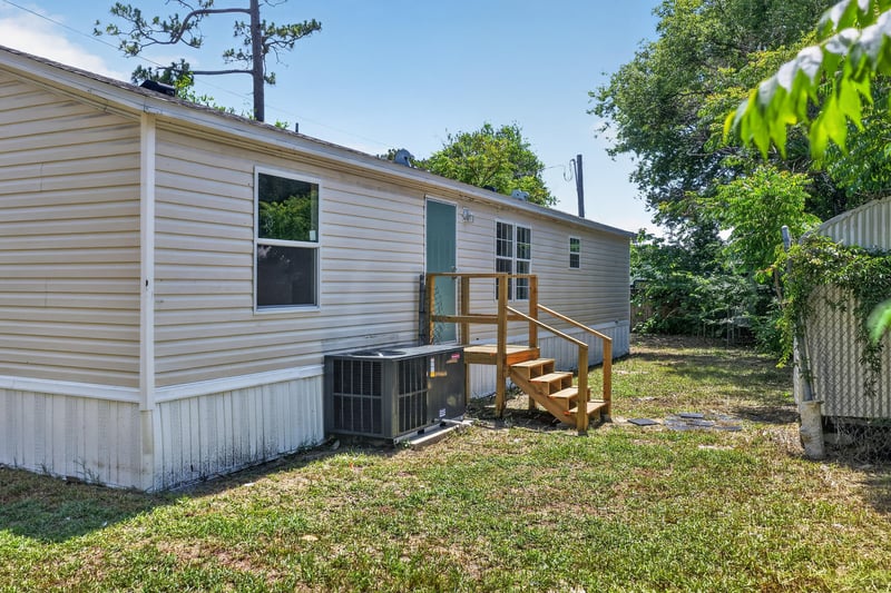Side exterior with wood steps and AC unit at 7603 Coach Park Dr, Jacksonville, FL 32244