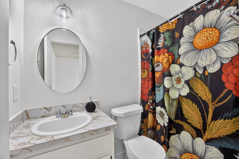 Bathroom with floral shower curtain and round mirror at 2829 Blackberry Ave