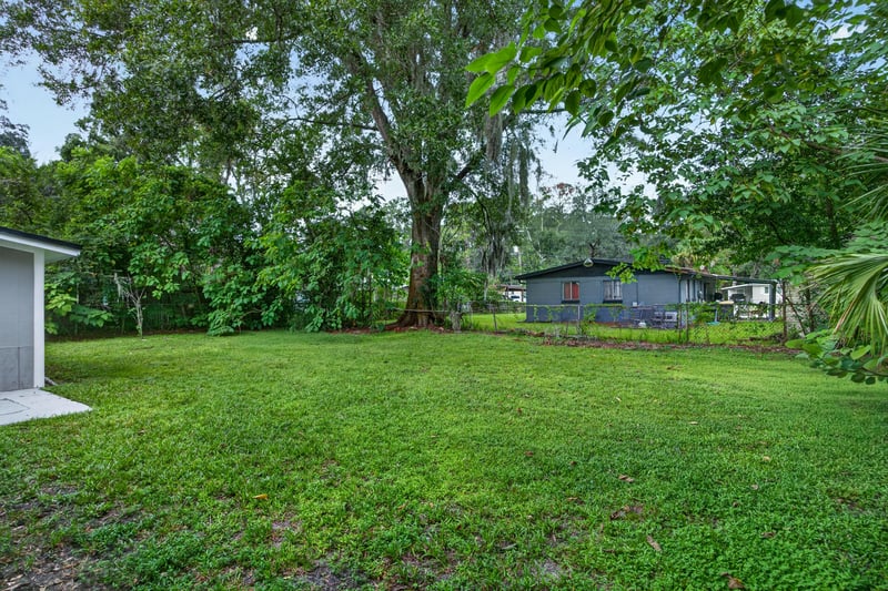 Backyard lawn bordered by trees at 6745 Jack Horner Ln, Jacksonville, FL 32210