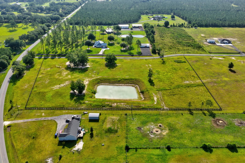 Aerial view of a pond and home site surrounded by open land at 7500 Lucky Seven Rnch Rd, Macclenny, FL