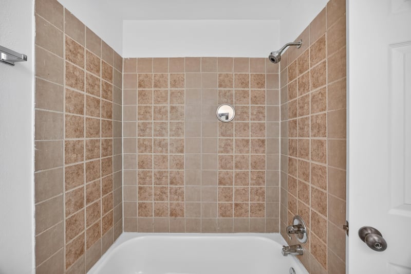 Bathroom shower and tub with tan tile at 3801 Crown Point Rd unit 2061, Jacksonville, FL 32257