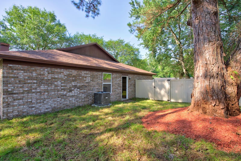 Side exterior with brick wall and AC unit at 8453 Boysenberry Ln W, Jacksonville, FL