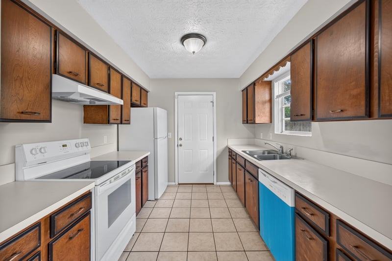 Kitchen with white appliances, tile floor, and wood cabinets at 1083 Stokes St, Jacksonville, FL