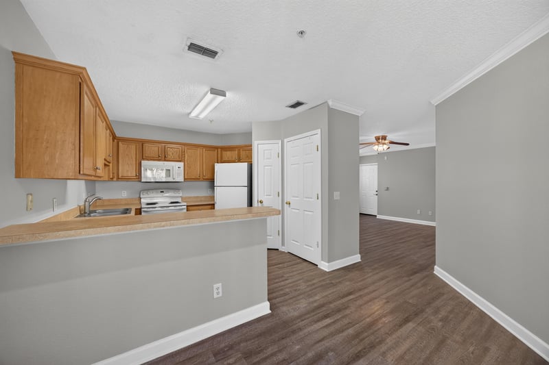 Kitchen with white appliances and wood cabinets at 1701 The Greens Way 1415, Jacksonville Beach, FL 32250