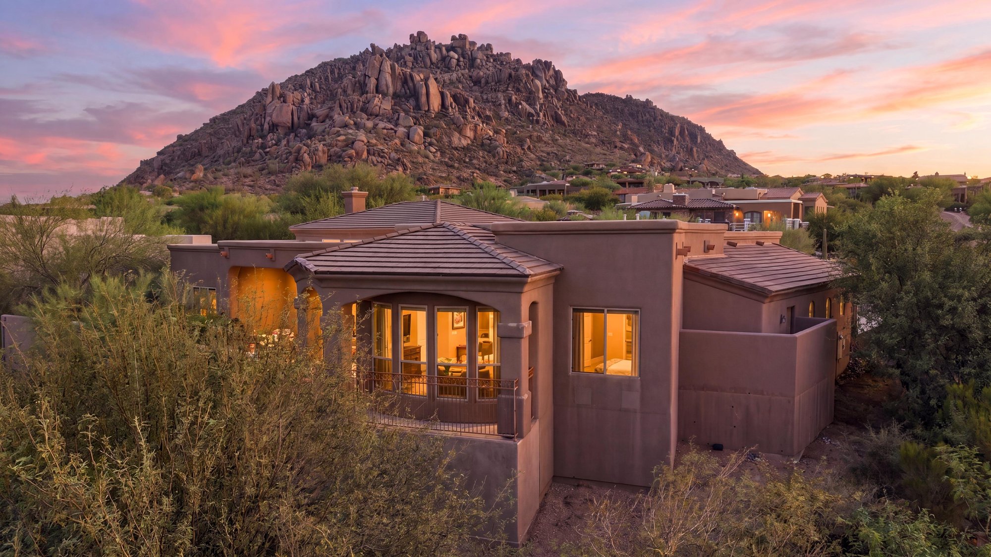 Virtual twilight of a desert home below a boulder-topped peak