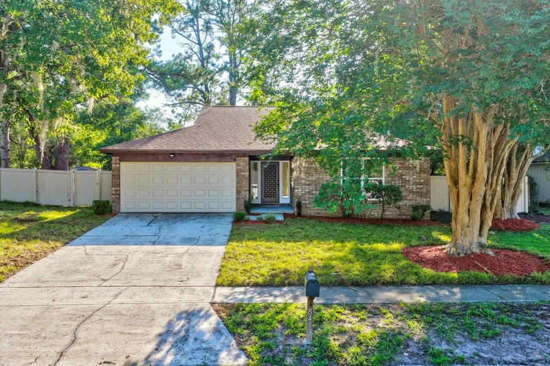 Front exterior close-up of garage door and mulched flower beds at 8453 Boysenberry Ln W, Jacksonville, FL