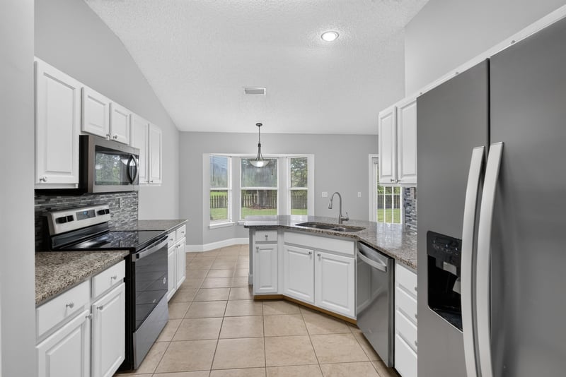Kitchen with white cabinets and stainless appliances at 12949 Chets Creek Dr S, Jacksonville, FL 32224