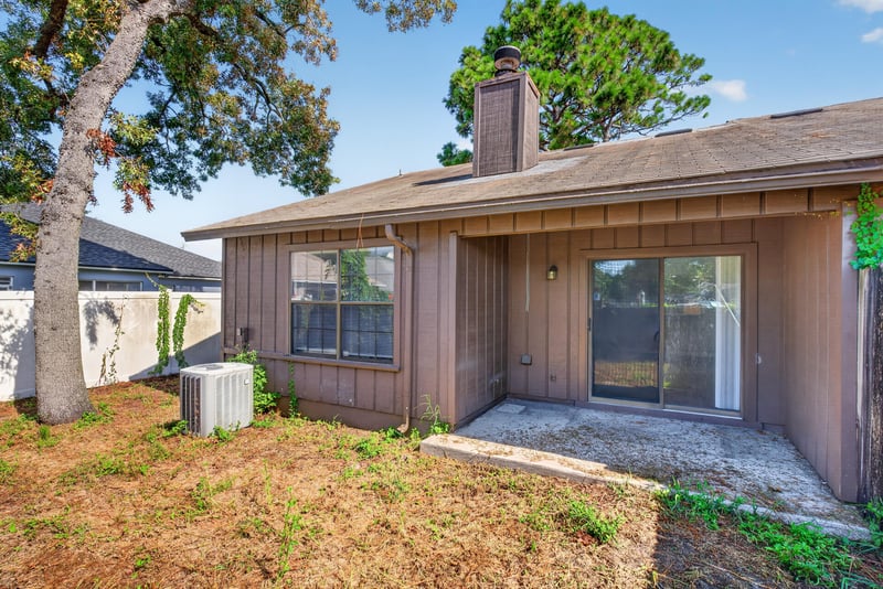 Back exterior with chimney and patio door at 8010 International Village Dr, Jacksonville, FL 32277