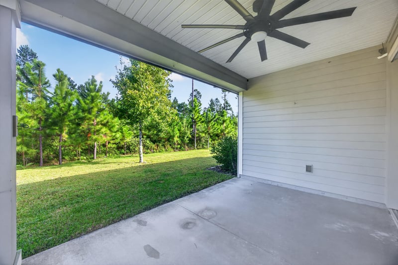 Covered patio with ceiling fan overlooking trees at 75875 Saffron Ln, Yulee, FL 32097