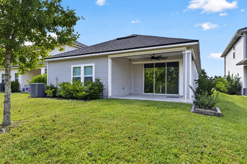 Back exterior with covered lanai and sliding doors at 75875 Saffron Ln, Yulee, FL 32097