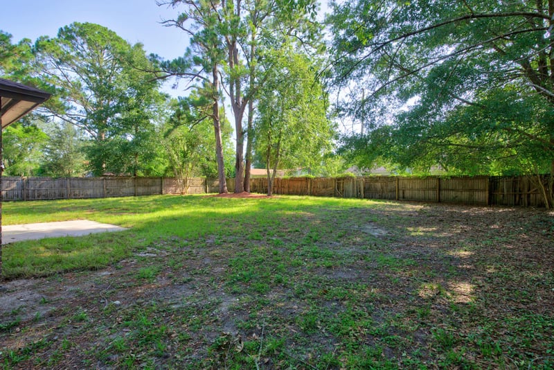Backyard lawn bordered by wood fencing at 8453 Boysenberry Ln W, Jacksonville, FL