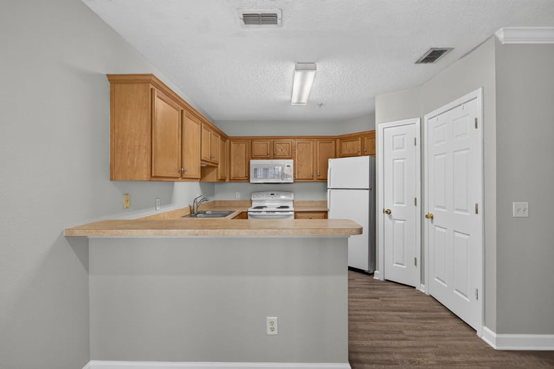 Kitchen with wood cabinets and breakfast bar at 1701 The Greens Way 1415, Jacksonville Beach, FL 32250