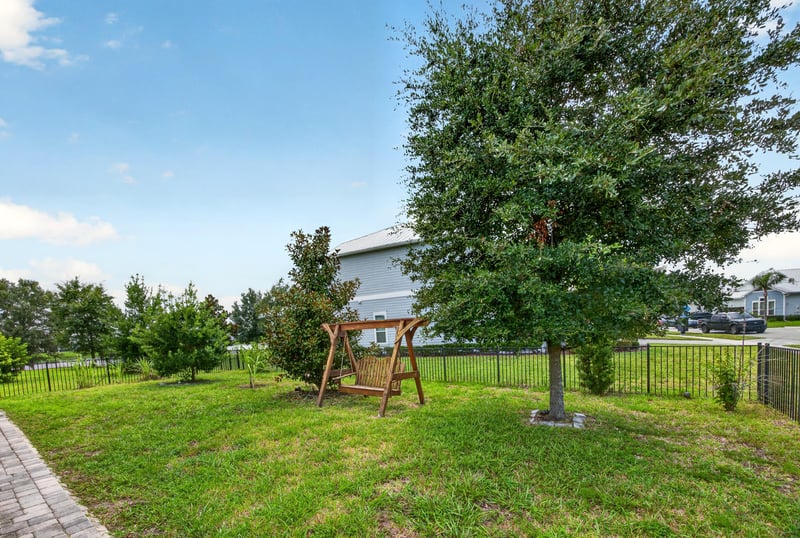 Fenced backyard with a shade tree and swing at 91 Tilloo Ct, St. Johns, FL