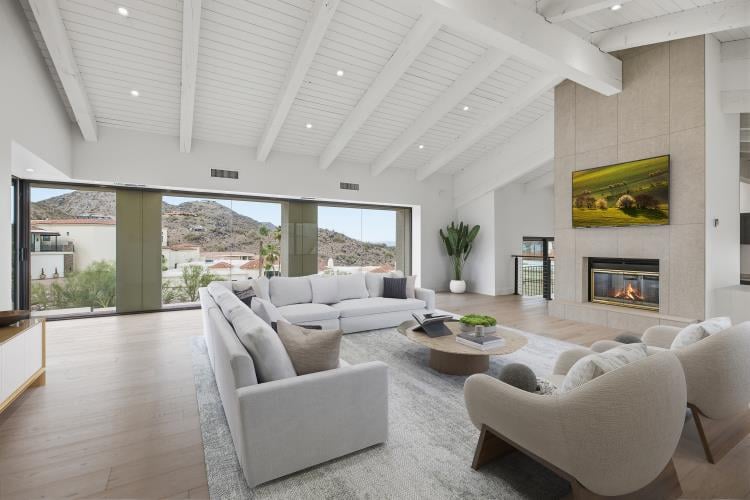 Great room with a beamed ceiling and fireplace, virtually staged