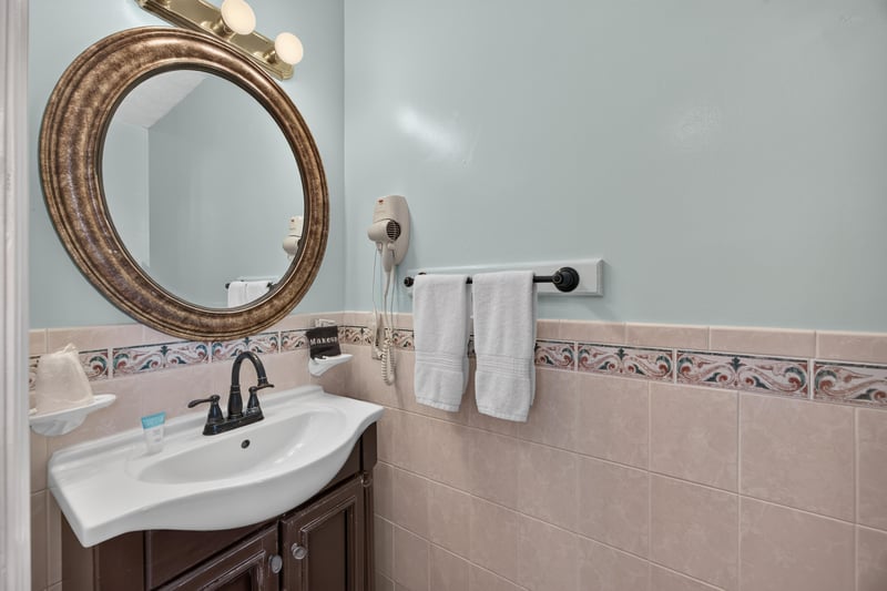 Bathroom with a pedestal sink and round mirror at 115 Cordova St, St. Augustine, FL