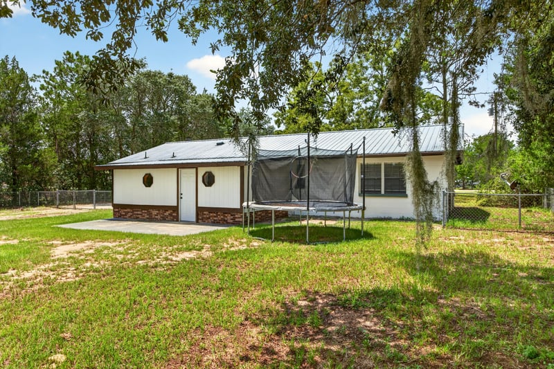 Rear exterior with detached garage and oak tree at 6757 Deer Springs Rd, Keystone Heights, FL 32656