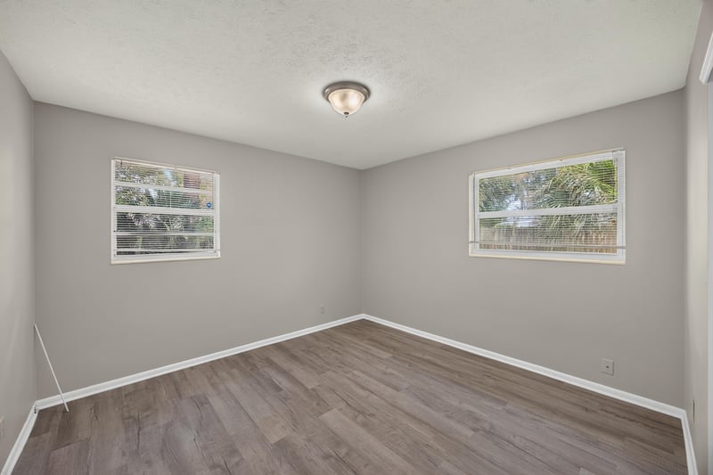 Bedroom with wood-look flooring and two windows at 5527 Beney Rd, Jacksonville, FL 32207