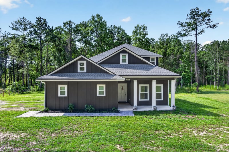 Front exterior with dark board-and-batten siding and covered porch at 2817 Camel Cir, Middleburg, FL