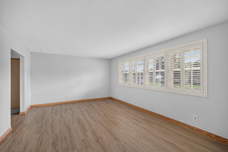 Empty living room with wood-look floors and plantation shutters at 1834 Memory Ln, Jacksonville, FL