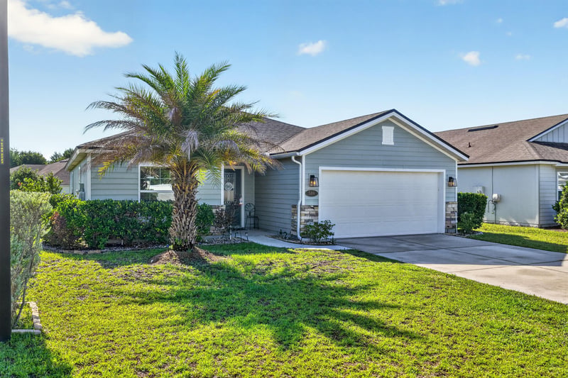 Front exterior with palm tree and two-car garage at 589 Seville Pkwy, St. Augustine, FL