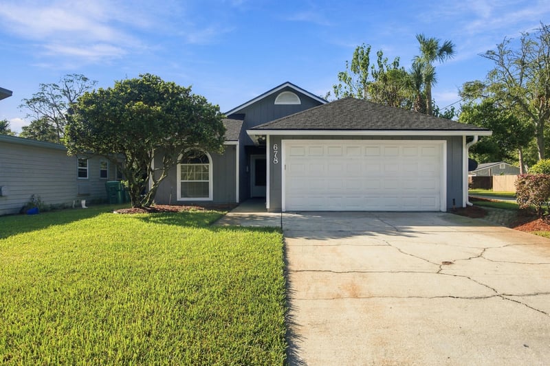 Front exterior with garage doors and landscaping at 678 5th Ave N, Jacksonville Beach, FL 32250