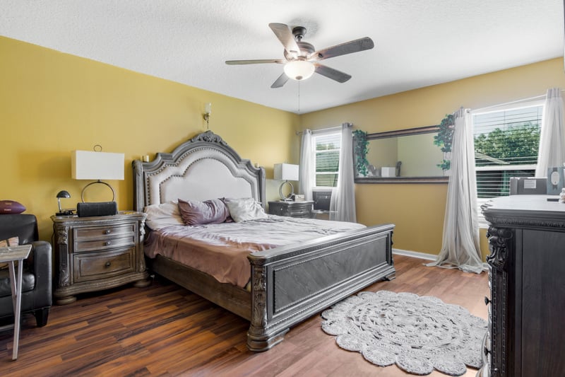 Primary bedroom with upholstered bed and windows at 7392 Timber Falls Ct