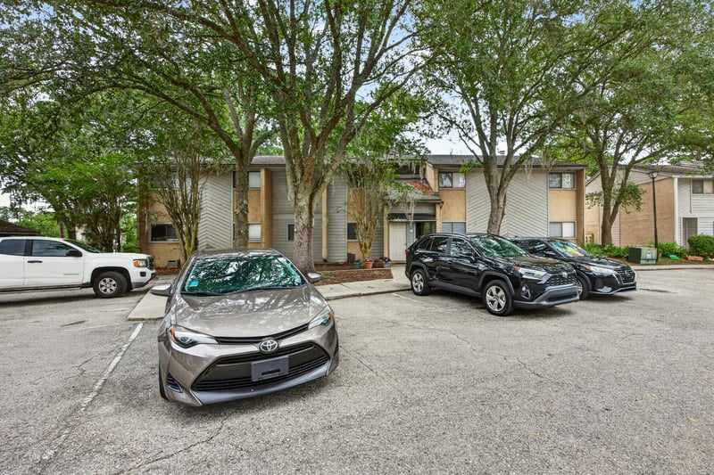 Condo building exterior with parking and trees in Jacksonville, FL