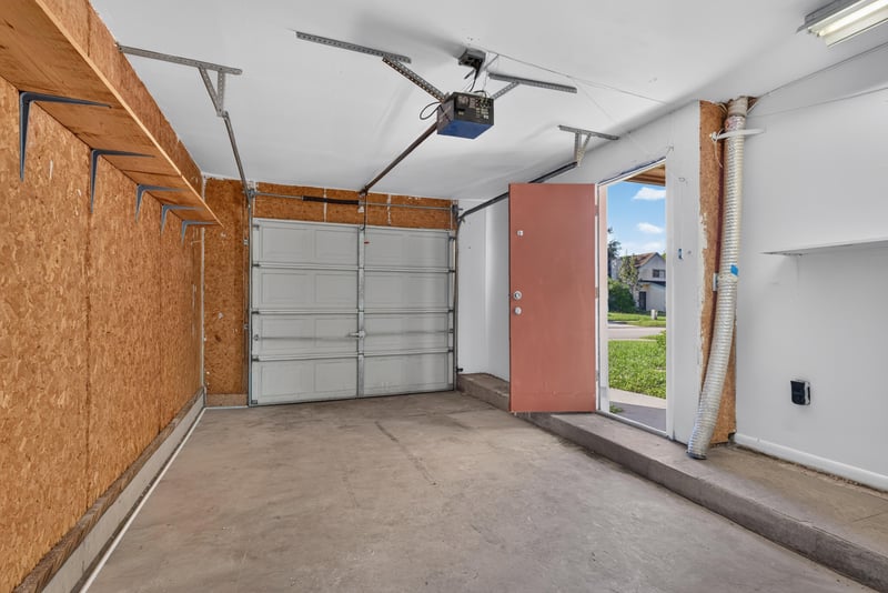 Garage interior with storage shelving and red door at 8177 Virgo St, Jacksonville, FL 32216