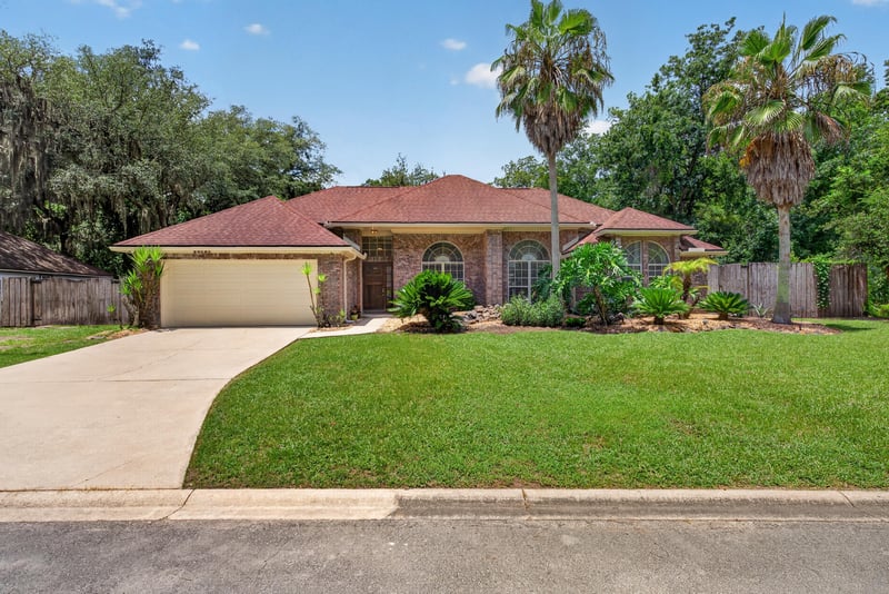 Front exterior with driveway and mature trees at 12810 Swamp Owl Ln