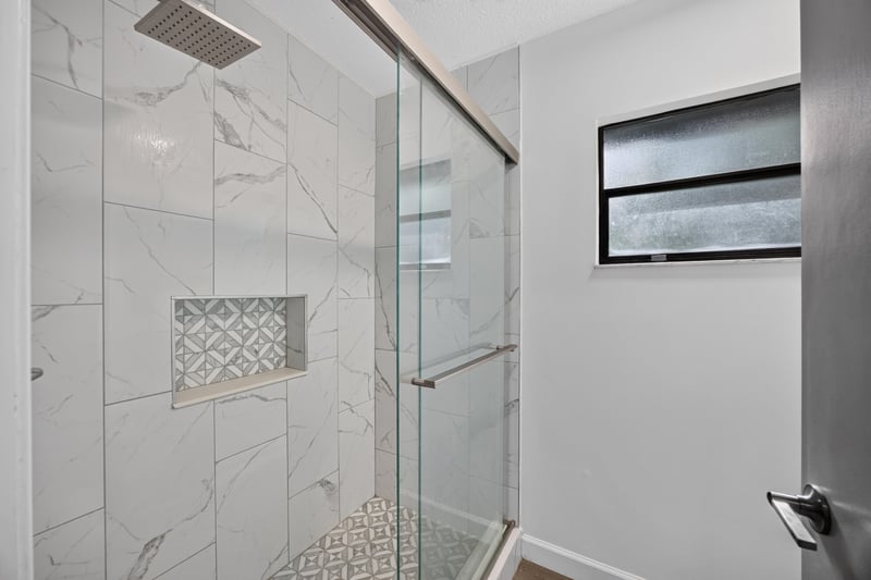Bathroom shower with tile surround and window at 551 Deltona Blvd, St. Augustine, FL 32086