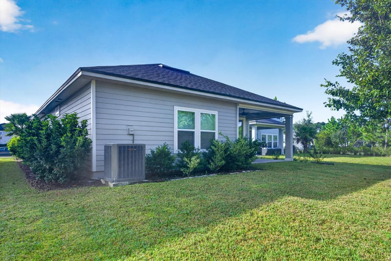 Back exterior with patio and grass yard at 75875 Saffron Ln, Yulee, FL 32097