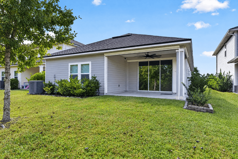Back exterior with covered patio and sliding doors at 75875 Saffron Ln, Yulee, FL 32097