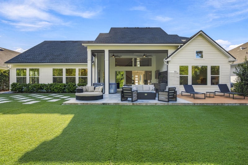 Rear exterior with covered patio and patterned turf yard at 907 Seagrove Dr, Ponte Vedra Beach, FL 32081