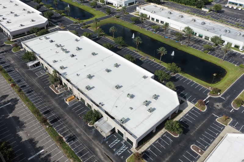 Aerial view of a roofline with pond and palm-lined parking at 10550 Deerwood Park Blvd, Jacksonville, FL 32256