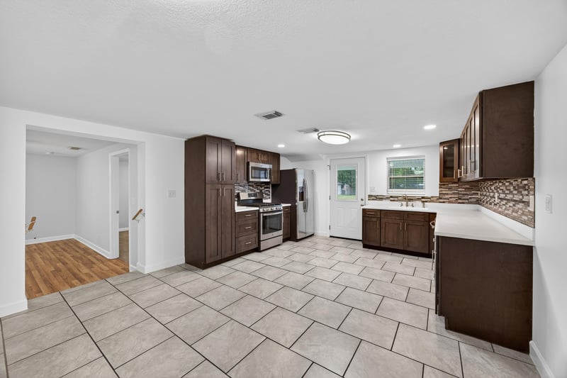 Open kitchen and living area with dark cabinets and tile floor at 1619 Hammond Blvd, Jacksonville, FL
