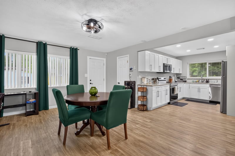 Dining area with green chairs and open kitchen beyond at 9506 Harriet Ave, Jacksonville, FL 32208