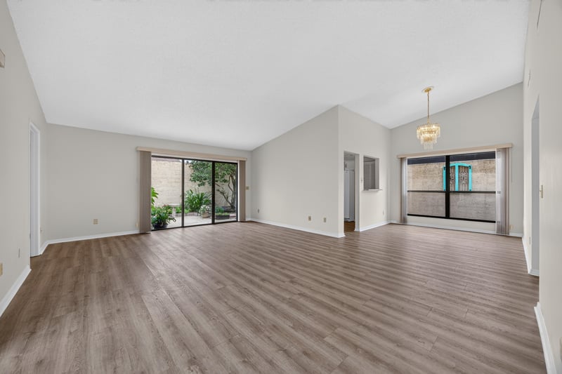 Empty living room with vaulted ceiling and wood-look floors at 3407 Fairbanks Grant Rd N, Jacksonville, FL 32223