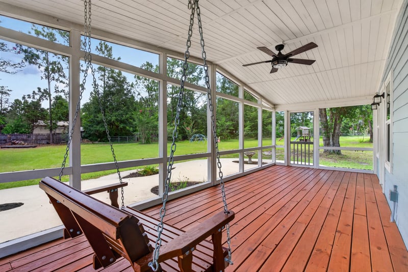 Screened porch with wooden porch swing and deck floor at 4890 McAllister Rd, Middleburg, FL 32068